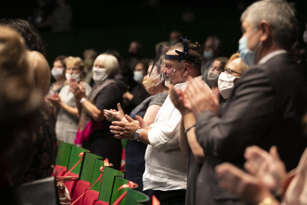 Publiczność Opery i Filharmonii Podlaskiej na stojąco oklaskuje artystów. Wszyscy mają na twarzach maseczki ochronne.