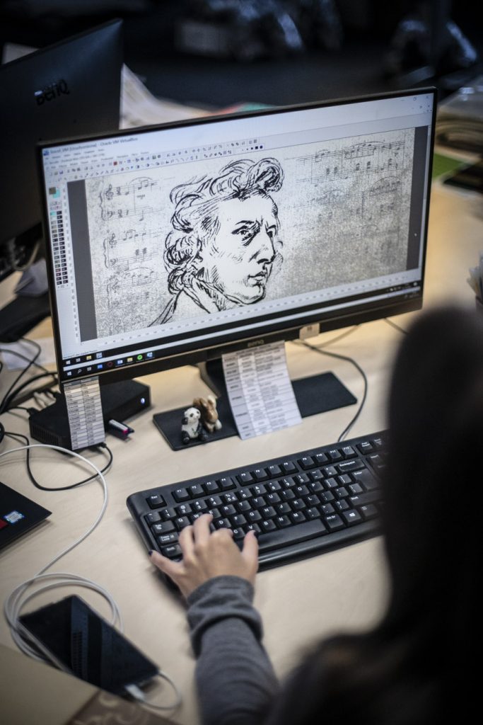 Na zdjęciu monitor komputera. Na nim wyświetlona twarz Chopina, część szkicu z dywanu promującego koncerty w Operze.