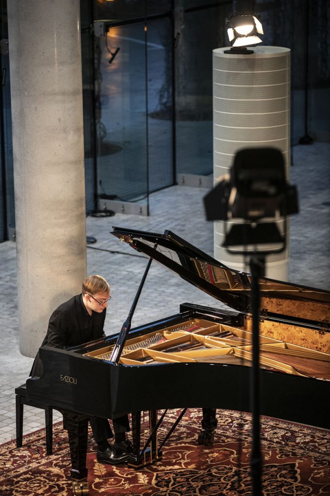 Zdjęcie zrobione z góry. Na foyer, mężczyzna gra na fortepianie.
