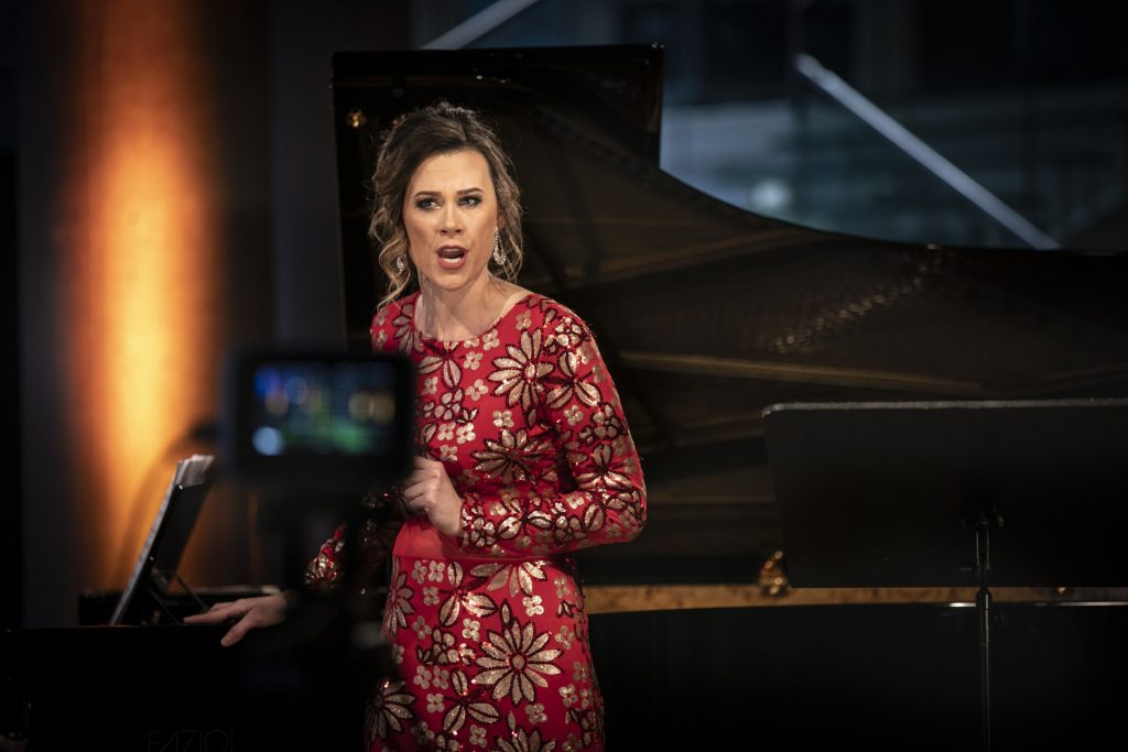 Koncert online z cyklu ''Jesień z Chopinem'' transmitowany z dolnego foyer. Przy fortepianie stoi kobieta w długiej, czerwonej sukni. Śpiewa.