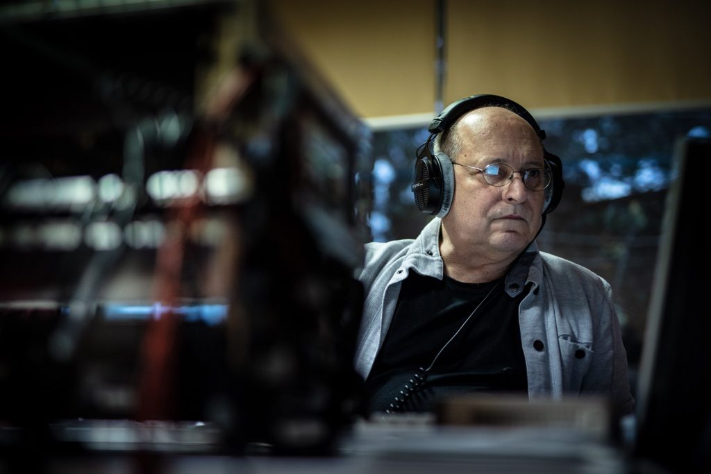 Mężczyzna w słuchawkach przed monitorem komputera.
