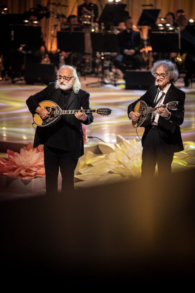 Zbliżenie na dwóch mężczyzn w czarnych garniturach grających na mandolinach.