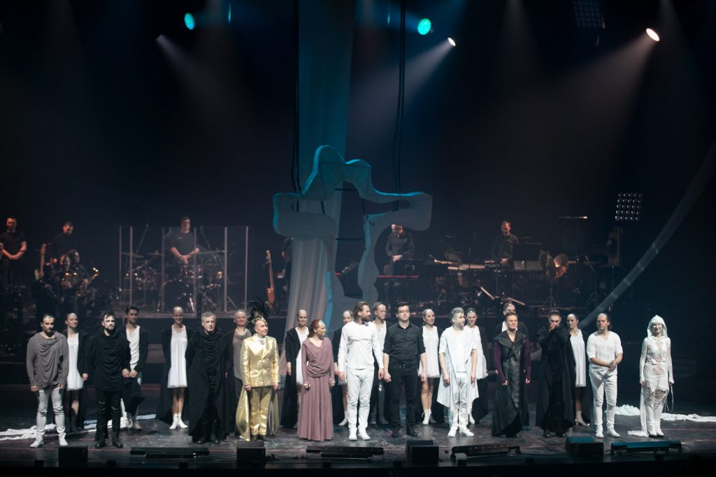 Na scenie stoją w rzędach wykonawcy musicalu ''Jesus Christ Superstar''. Za nimi z tyłu na podeście stoi orkiestra.