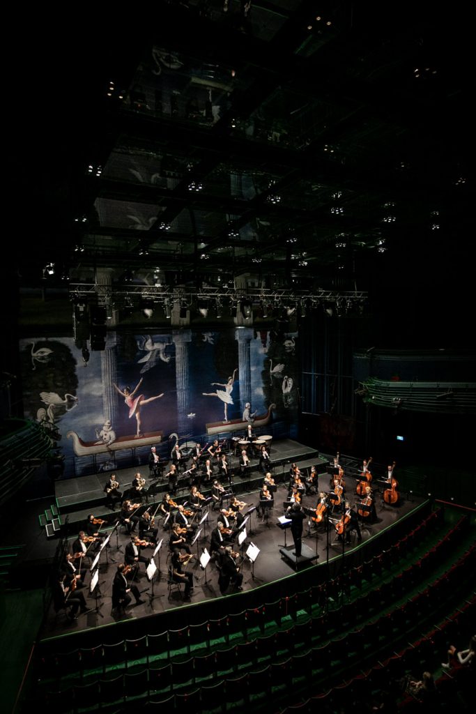 Widok z góry. Na scenie orkiestra wraz z dyrygentem podczas koncertu.