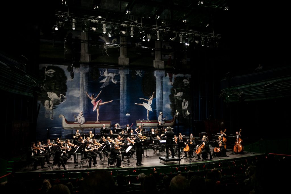 Na scenie orkiestra wraz z dyrygentem podczas koncertu.